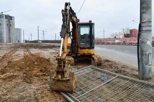 tractor de excavadora pesada industrial de gran alcance amarillo brillante, bulldozer, equipo de construcción especializado para la reparación de carreteras durante la construcción de un nuevo microdistrito en una gran ciudad foto