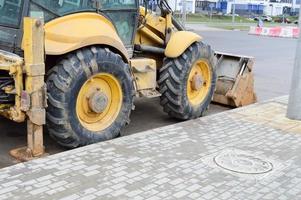 tractor de excavadora pesada industrial de gran alcance amarillo brillante, bulldozer, equipo de construcción especializado para la reparación de carreteras durante la construcción de un nuevo microdistrito en una gran ciudad foto