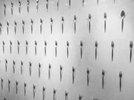 The pattern of a variety of metal forks, cutlery on the wall on a black and white background. Texture photo