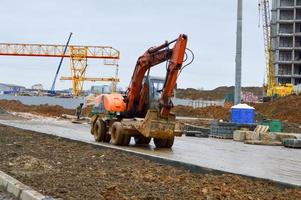 tractor de excavadora pesada industrial de gran alcance amarillo brillante, bulldozer, equipo de construcción especializado para la reparación de carreteras durante la construcción de un nuevo microdistrito en una gran ciudad foto