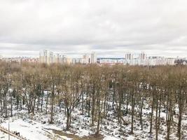 The view from the window of the old city cemetery in the park from a height with trees and houses in the winter. Panorama of the city photo