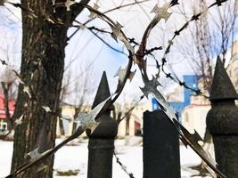 Iron metal sharp dangerous protective barbed wire on the fence with spikes and stakes against the sky photo