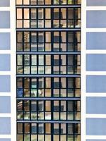 Texture of blue mirrored windows and balconies of a high modern monolithic-frame building, house, new buildings, skyscraper. The background. Texture photo