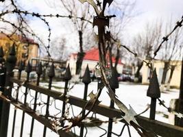 Iron metal sharp dangerous protective barbed wire on the fence with spikes and stakes against the sky photo