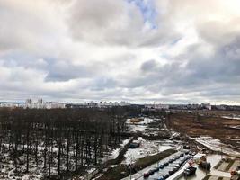 The view from the window of the old city cemetery in the park from a height with trees and houses in the winter. Panorama of the city photo