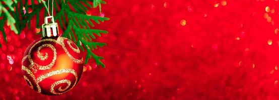 Beautiful Christmas ball on red shiny background. New Year concept, banner format. photo