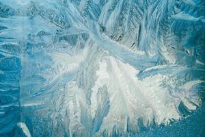 Winter frosty patterns on glass. Christmas festive background. Shiny ice crystals on window. photo