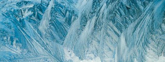 Frosty patterns on glass. Christmas background. Ice on winter window. Abstract crystals close up. photo