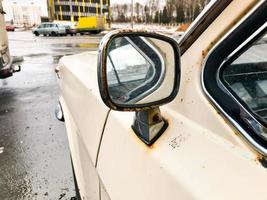 Old retro vintage hipster rusty oxidized chrome-plated metallic silver mirror of a retro antiquan white American passenger car Maskar from the 60s, 70s, 80s, 90s, 2000s photo