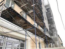 Repair work on the facade of the building with the help of wooden scaffolding, structures, restoration of the old house photo