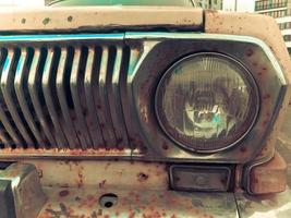 An old retro vintage hipster rusty oxidized chrome-plated metallic silver radiator grille and a round glass retro spotlight of an antiquan white white American car from the 60s, 70s, 80s, 90s, 2000s photo