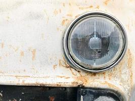 una vieja rejilla de radiador de plata metálica cromada oxidada hipster retro vintage y un foco retro de vidrio redondo de un automóvil americano blanco blanco antiguo de los años 60, 70, 80, 90, 2000 foto