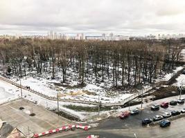 The view from the window of the old city cemetery in the park from a height with trees and houses in the winter. Panorama of the city photo