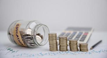 Concept to saving money income for study, Calculating student finance costs and investment budget loan. close-up education object with stack money coin-cash dollar and glass jar on background. photo