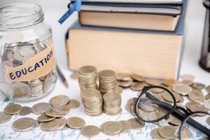 Concept to saving money income for study, Calculating student finance costs and investment budget loan. close-up education object with stack money coin-cash dollar and glass jar on background. photo