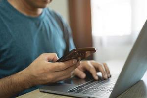 Man using smartphone after working with laptop on table, businessman using mobile phone to search or social media or shopping online. Business concept smart phone technology conversation conferrence. photo