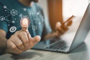 Man using fingerprint scan provides security access with biometrics identification on screen and using laptop and mobile. Business Technology Safety Internet Network Concept. The security scanning. photo