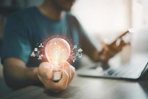 Man hand holding light bulb global Internet connection while working on laptop and mobile phone. Business global internet connection application technology and digital marketing financial and banking. photo