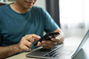 Man using smartphone after working with laptop on table, businessman using mobile phone to search or social media or shopping online. Business concept smart phone technology conversation conferrence. photo