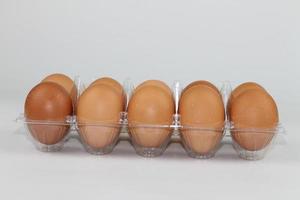 Close-up view of raw chicken eggs in egg box on white white background photo