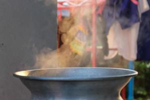 Traditional silver steamer pot with white smoke while cooking photo