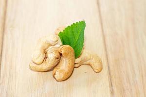 many cashew nut on wooden table with green leaf use for cooking photo