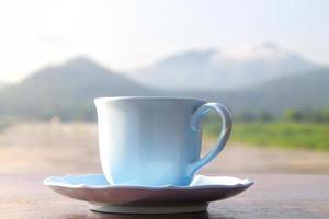 White coffee cup on mountain background in the morning near the river photo