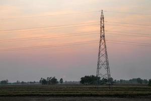 poste de alto voltaje, torre de alto voltaje con fondo de puesta de sol en el cielo. foto