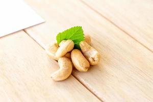 many cashew nut with green leaf on wooden table in studio photo