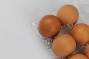 Close-up view of raw chicken eggs in egg box on white white background photo