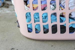 Pink Basket with dirty laundry on floor. photo