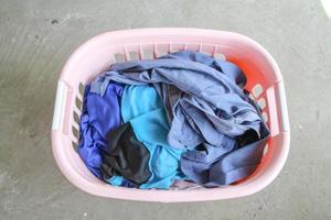 Pink Basket with dirty laundry on floor. photo