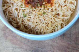 fideos instantáneos en un tazón azul sobre el fondo de madera. foto