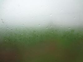 Window glass with condensation high humidity , large droplets flow down , Green Natural water drop background. photo