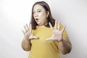 Beautiful Asian big sized woman wearing yellow shirt with hand gesture pose rejection or prohibition with copy space photo