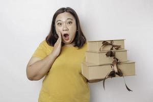 A shocked young Asian big sized woman is wearing yellow shirt and holding presents boxes and shopping bags. photo