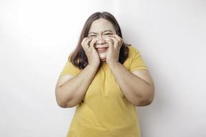 A portrait of an Asian big sized woman wearing a yellow t-shirt isolated by white background looks depressed photo