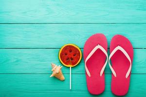 Pink flip flops with watermelon candy food and copy space on blue wooden background. Top view. Mock up. Copy space. Summer time photo