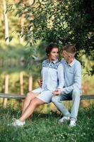 una pareja joven se abraza y se sienta cerca del lago en un día soleado. hombre y mujer en vacaciones de verano. concepto de familia encantadora. enfoque selectivo foto