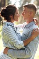 Cheerful young woman and man are hugging outdoors in summer park. Dating and romantic vacation. couple in love gently looking at each other on sunny day. Love and relationships between young people photo