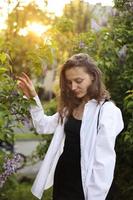 irreal impresionante hermosa mujer joven caminando en un verde florecido en primavera en un jardín de lavanda con un ramo de lilas en las manos. retrato romántico de moda de primer plano. oliendo las flores foto