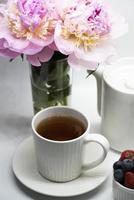Cup of tea, peony and berries photo
