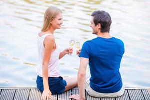 Cheers Beautiful young loving couple sitting at the quayside together and drinking Champaign photo