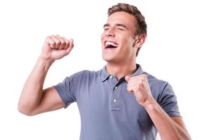 I am so happy Happy young man keeping eyes closed and gesturing while standing isolated on white background photo