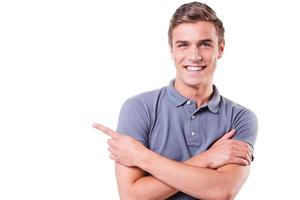 Look at this Handsome young man pointing away and smiling while standing isolated on white background photo