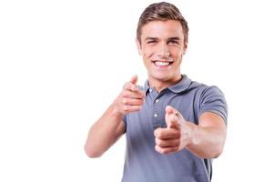 I choose you Handsome young man pointing you and smiling while standing isolated on white background photo