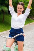 I love riding Happy young woman riding her bicycle and keeping arms raised photo