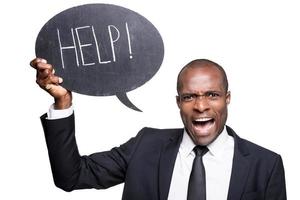 I need help Furious young African man in formalwear holding banner with help text while standing isolated on white background photo