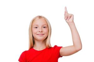 Look over there Cute little girl pointing up and looking at camera while standing isolated on white photo