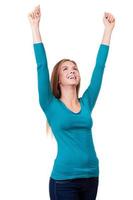 Victory is my second name Portrait of a beautiful young woman keeping her arms raised standing against white background photo